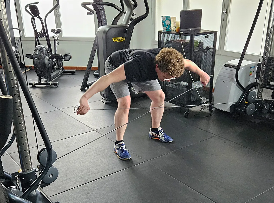 Mann beim vorgebeugten Training am Kabelzug im Studio