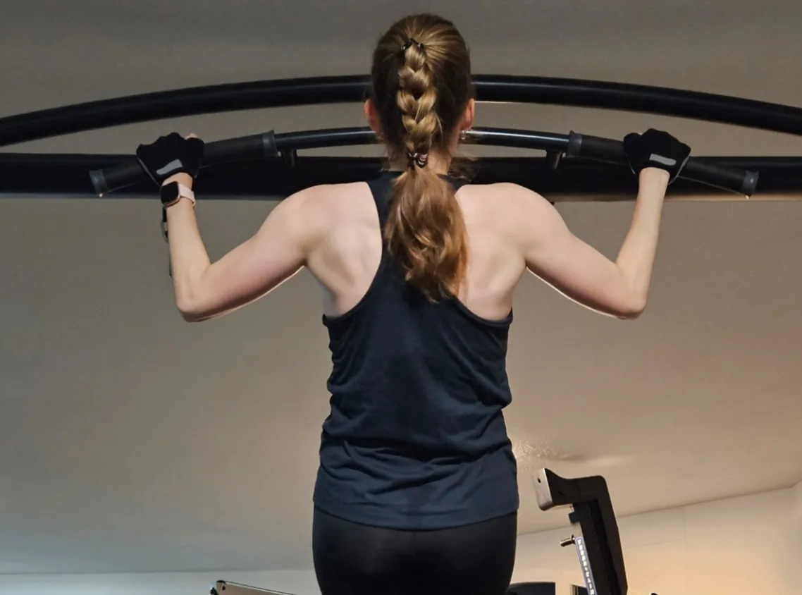 Frau beim Klimmzug an einer Trainingsstation im Studio